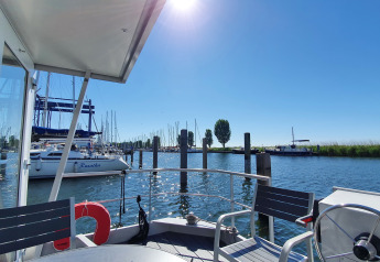 Udsigt fra en husbåd ved Havenlodge Lelystad i Marina Parcs med både og solrig blå himmel i Holland.