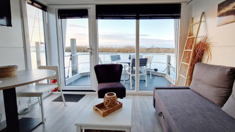 Interiør af en husbåd Havenlodge Lelystad ved Marina Parcs Lelystad, med udsigt over vandet og terrasse.