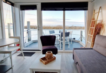 Interiør af en husbåd Havenlodge Lelystad ved Marina Parcs Lelystad, med udsigt over vandet og terrasse.