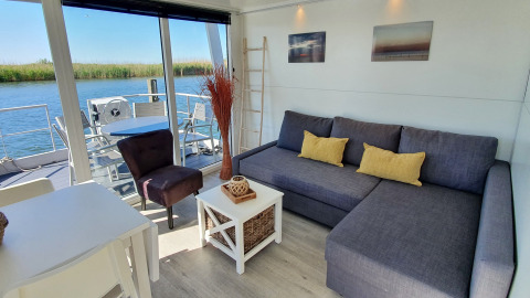Lyst og moderne husbådinteriør i Havenlodge Lelystad med udsigt over vandet ved Marina Parcs, Holland.