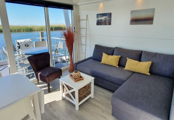 Lyst og moderne husbådinteriør i Havenlodge Lelystad med udsigt over vandet ved Marina Parcs, Holland.