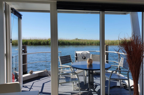 Vista desde una casa flotante en Marina Parcs Lelystad, Países Bajos, con terraza y asientos hacia el agua.