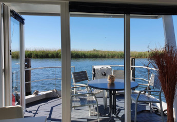 Uitzicht vanaf een havenlodge bij Marina Parcs Lelystad, Nederland, met terras en zithoek aan het water.