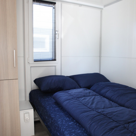 Moderne slaapkamer met donkerblauw beddengoed in Havenlodge Lelystad, Marina Parcs, Nederland.