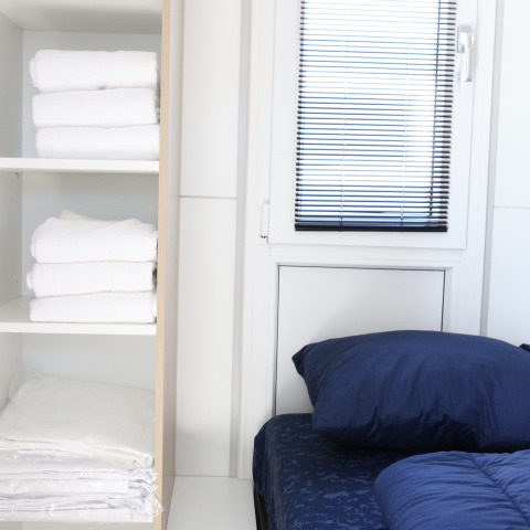 Dormitorio moderno en el houseboat Havenlodge Lelystad con estantes con toallas y sábanas en los Países Bajos.