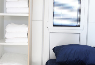Dormitorio moderno en el houseboat Havenlodge Lelystad con estantes con toallas y sábanas en los Países Bajos.