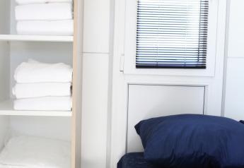 Chambre moderne sur la péniche Havenlodge Lelystad avec étagères de serviettes et draps aux Pays-Bas.