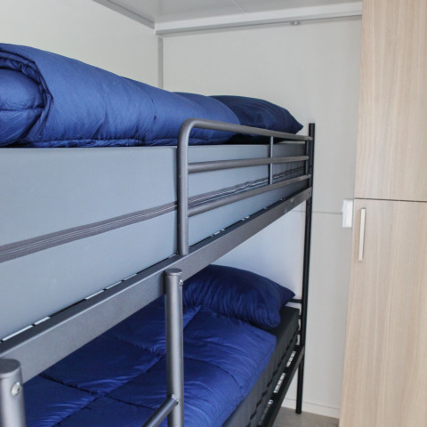 Literas con ropa de cama azul en una cabina compacta de la casa flotante Havenlodge Lelystad en Marina Parcs, Países Bajos.