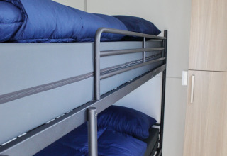 Literas con ropa de cama azul en una cabina compacta de la casa flotante Havenlodge Lelystad en Marina Parcs, Países Bajos.