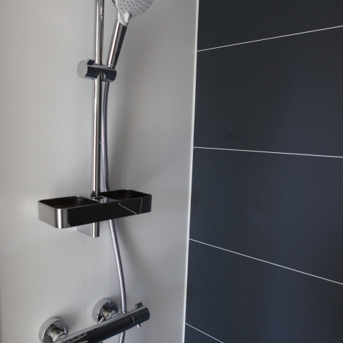 Moderne douche op een woonboot bij Havenlodge Lelystad, Marina Parcs Lelystad in Nederland met donkere tegels.