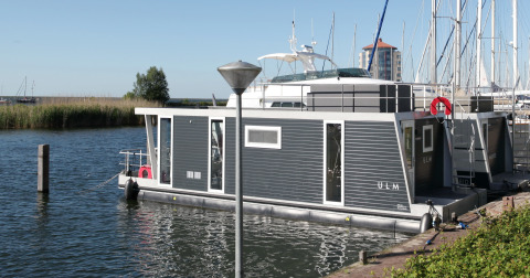 Moderne husbåd Havenlodge Lelystad fortøjet ved Marina Parcs Lelystad i Nederlandene på en solrig dag.