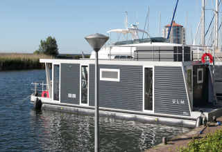 Casa flotante Havenlodge Lelystad atracada en Marina Parcs Lelystad de los Países Bajos en un día soleado.