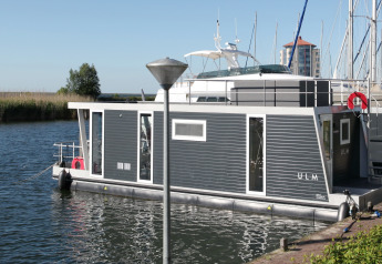 Moderne husbåd Havenlodge Lelystad fortøjet ved Marina Parcs Lelystad i Nederlandene på en solrig dag.