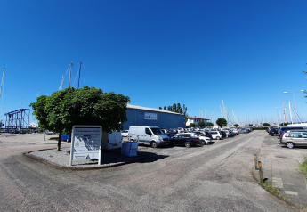 Parkplatz am Yachthafen Marina Parcs Lelystad mit Autos, Booten und blauem Himmel in den Niederlanden.