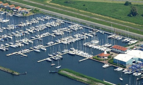 Vista aérea de Marina Parcs Lelystad en los Países Bajos con numerosos barcos y casas flotantes en el puerto.