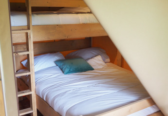 A photo of bunk beds with light wooden frames inside a safari tent at Camping Le Bois de la Gachère, France.