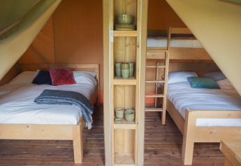 Innenansicht eines Safari-Zeltes auf Camping Le Bois de la Gachère in Frankreich mit Bett und Etagenbetten.