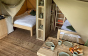 Indvendigt udsyn fra en safaritelt ved Camping Le Bois de la Gachère i Frankrig med senge og spisebord.