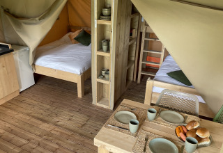 Innenansicht eines Safari-Zeltes auf Camping Le Bois de la Gachère in Frankreich mit Betten und Essbereich.