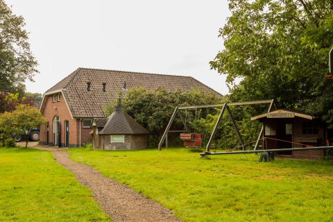 Parque infantil y casa rural de vacaciones en Feather Down Het Boshuis en Gelderland, Países Bajos, rodeado de verde.