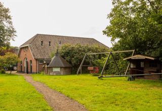 Playground and rural holiday house at Feather Down Het Boshuis holiday park in Gelderland, Netherlands, greenery view.