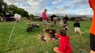 Niños y adultos asan malvaviscos en una fogata en Feather Down De Brabantse Hei, parque en Países Bajos.