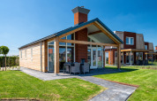 Et moderne Eneva-disabled lodge ved Tusken de Marren i Holland, med grønne græsplæner og terrasse.