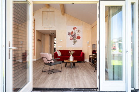 Eingang zur Eneva disabled Lodge mit moderner Einrichtung, rotem Sofa und Blumenbild an der Wand in Holland.