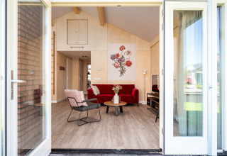 Ingang van Eneva disabled lodge bij Tusken de Marren, met rode bank en bloemenkunst aan de muur in Nederland.