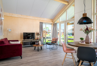 Stijlvolle leefruimte in Eneva disabled lodge, Tusken de Marren, Nederland, met grote ramen en zicht op het water.