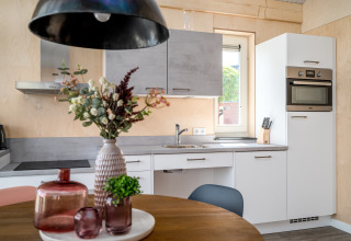 Cocina moderna y accesible en la Eneva lodge de Tusken de Marren, Países Bajos, con flores decorativas.