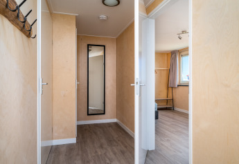 Heldere gang met houten vloer, spiegel en slaapkamer in Eneva disabled lodge bij Tusken de Marren.