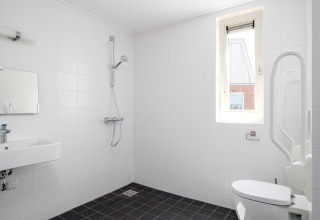Salle de bain accessible à Eneva Disabled, Tusken de Marren, avec douche, WC avec barre d'appui et lavabo.