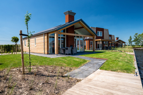 Toegankelijke Eneva lodge bij Tusken de Marren, Nederland, met moderne veranda, tuin en waterzicht.