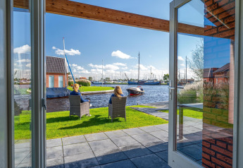 Udsigt fra Eneva disabled-lodge på Tusken de Marren, Holland, med personer ved vandet og både i baggrunden.