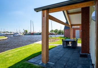 Terrasse mit Blick auf einen Kanal mit Booten, Eneva disabled Lodge bei Tusken de Marren, Niederlande.