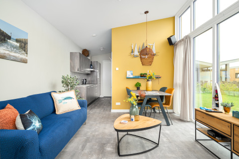 Living room in Knilles lodge at Tusken de Marren, Netherlands, with modern decor, large windows, and dining area.