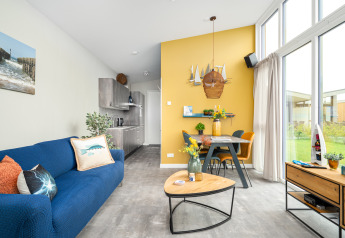 Living room in Knilles lodge at Tusken de Marren, Netherlands, with modern decor, large windows, and dining area.