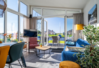 Lichte woonkamer in Knilles-lodge aan het water bij Tusken de Marren, Nederland, met uitzicht op het terras.