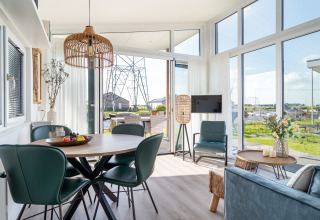 Moderno lodge Knilles sull’acqua a Tusken de Marren, Paesi Bassi, con grandi finestre e arredamento accogliente.