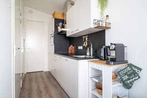 Cocina moderna y compacta en Knilles junto al agua en Tusken de Marren, Países Bajos, con muebles blancos y cafetera.