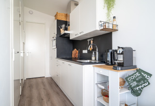 Moderne, kompaktes Küche in Knilles am Wasser bei Tusken de Marren in den Niederlanden, weiße Schränke, Kaffeemaschine.