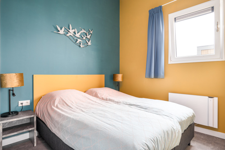 Bedroom at Knilles lodge by the water at Tusken de Marren, Netherlands, with two single beds and wall art.
