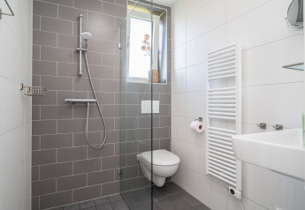 Baño moderno con ducha tipo lluvia, inodoro suspendido y toallero calefaccionado en Knilles, Tusken de Marren.