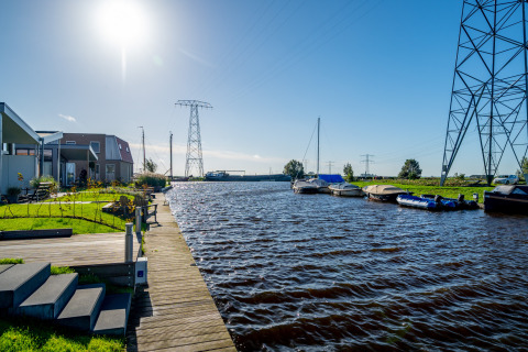Vista soleada al agua en el lodge Knilles con barcos y casas modernas en Tusken de Marren, Países Bajos.
