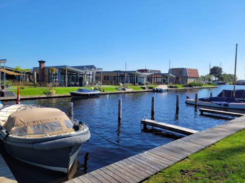 Knilles-lodgen ved vandet ved Tusken de Marren i Holland med både, moderne hytter og blå himmel.