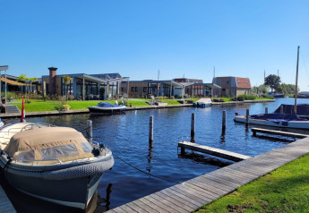 Lodge Knilles aan het water bij Tusken de Marren in Nederland, met boten, dokken en moderne huisjes.