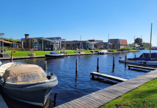 Knilles-lodgen ved vandet ved Tusken de Marren i Holland med både, moderne hytter og blå himmel.