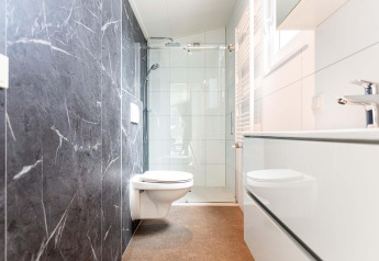 Moderne badkamer in een glampingverblijf met zwevend toilet, douchecabine en stijlvol interieur.