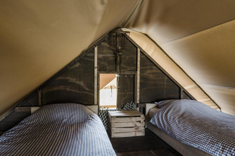 Indretning af en safari-teltlejlighed med to enkeltsenge og ternede dyner i Beach Lodge ved Duynpark Het Zwanenwater.